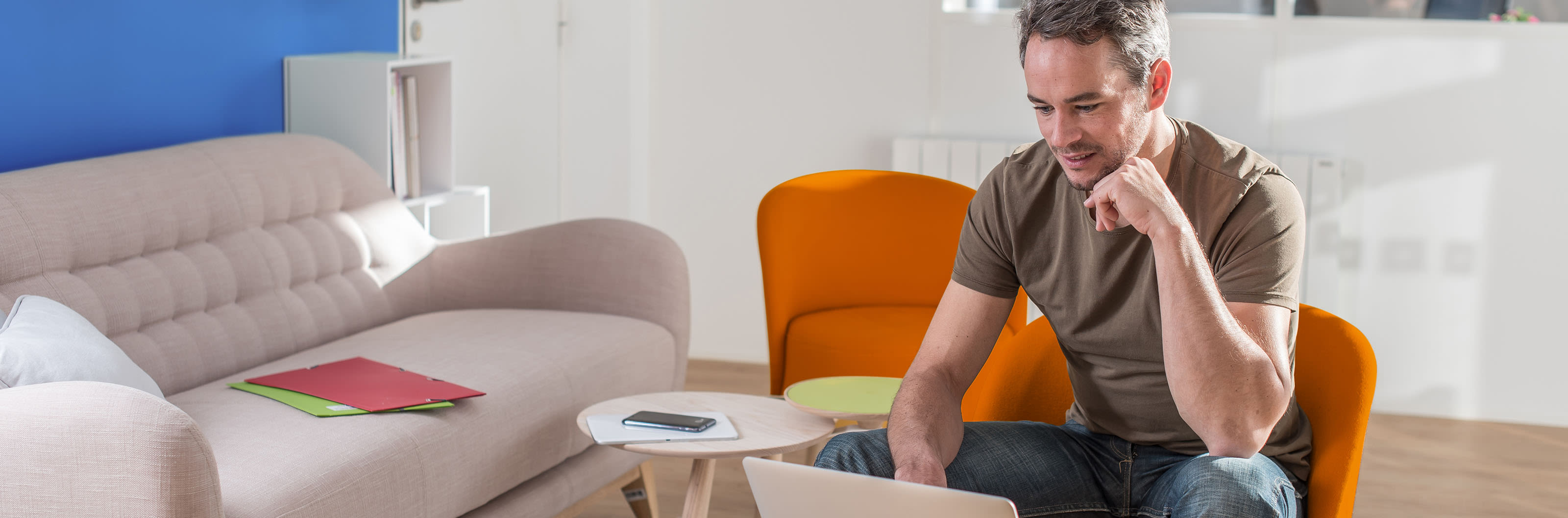 Mann sitzt auf Couch und schaut auf Tablet